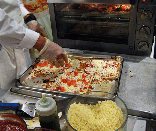Detail of photo by Elizabeth Bland at: https://cheesemistress.wordpress.com/2015/03/16/matzo-pizza-at-the-manischewitz-experience-2015/